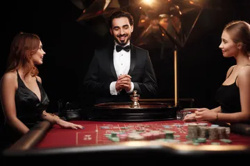 1111DB Live Casino — Join thrilling real-dealer tables A professional dealer in a tuxedo greeting players at the roulette table, symbolizing the authentic live casino feel at 1111DB.