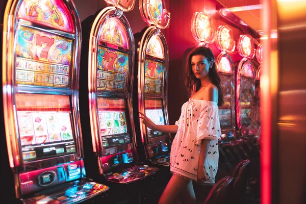1111DB Slots — Thousands of exciting themes and jackpots A stylish woman beside vibrant slot machines displaying glowing sevens, showcasing the variety of top slots at 1111DB.