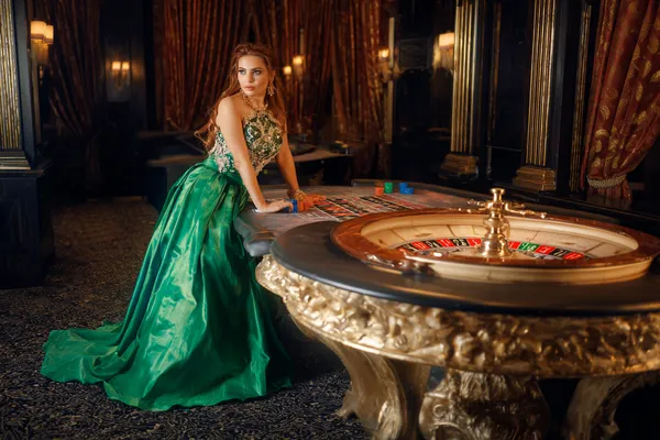 1111DB — A high-class gaming experience without limits A woman in a luxurious green gown next to an ornate roulette wheel, capturing the upscale casino mood of 1111DB.